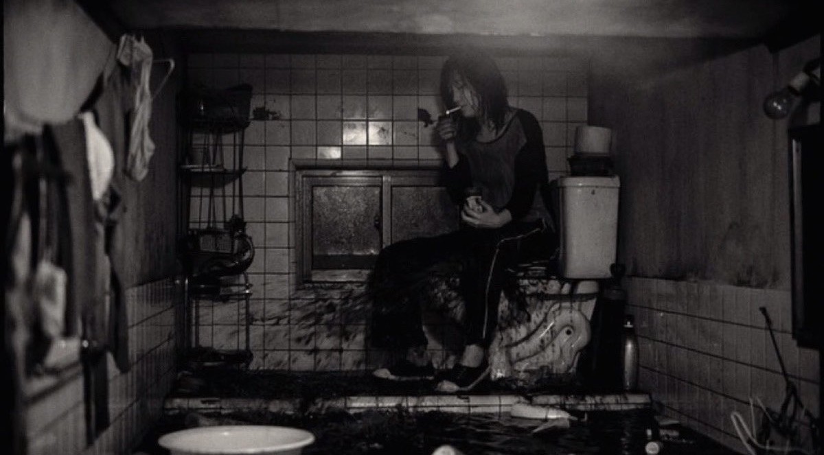 水浸しの半地下で諦めてタバコを吸うギジョン（映画「パラサイト 半地下の家族」より）